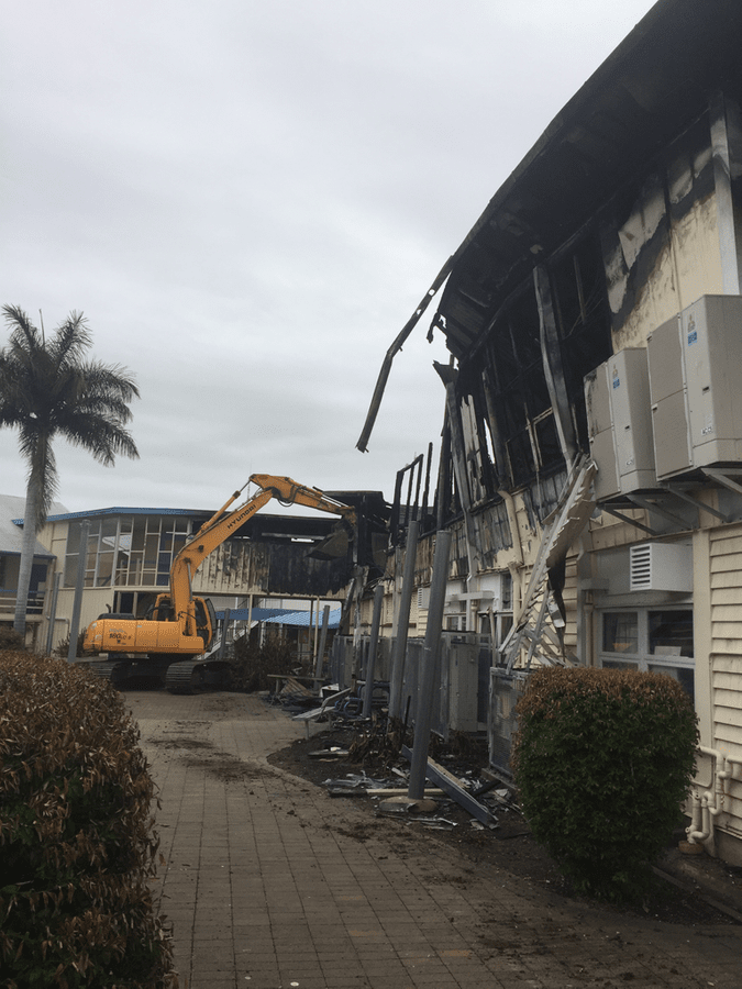 Excavator working through a fire-damaged building clearance