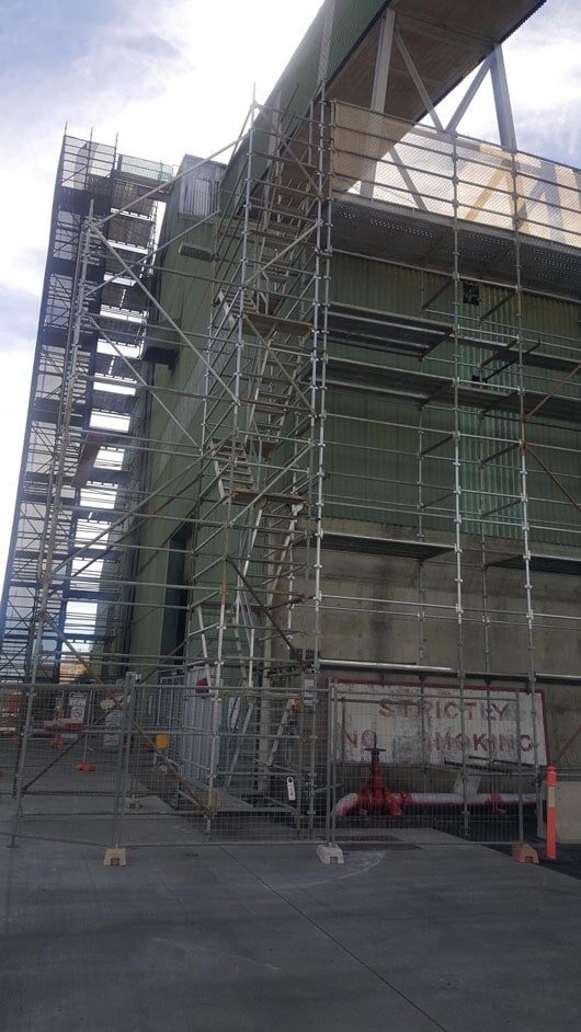 Industrial tank fully wrapped in shrink containment over Kwik Lift scaffolding